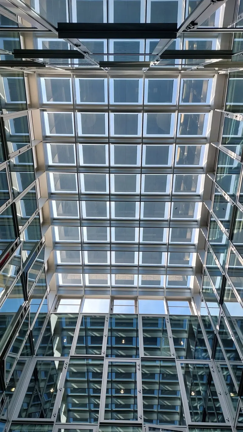 Looking up at the glass-and-steel atrium roof of an EPFL building