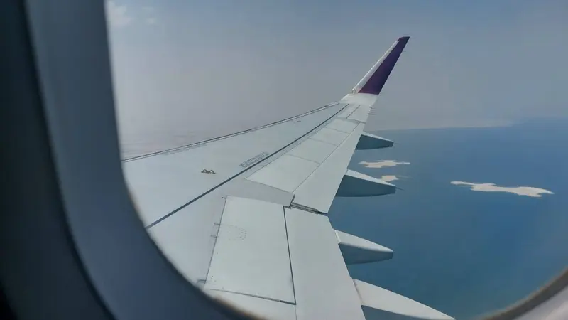 Airplane wing above the sea, seen from the window seat