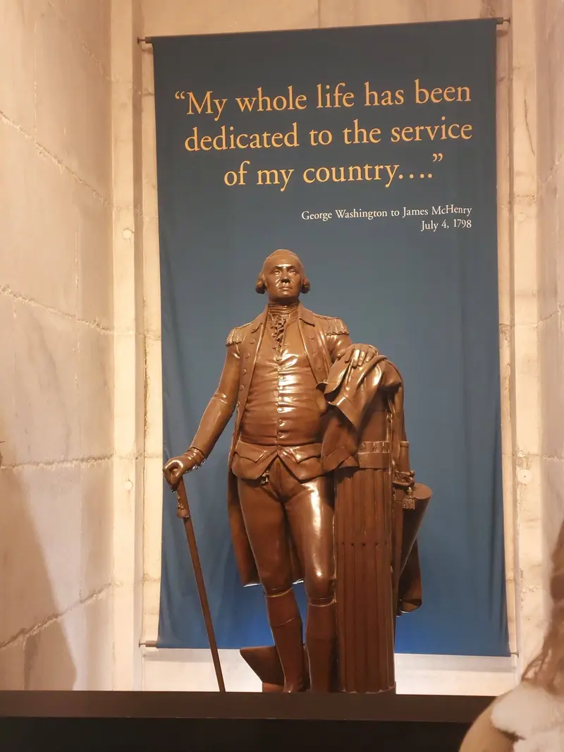 Statue of George Washington in front of a banner with one of his quotes