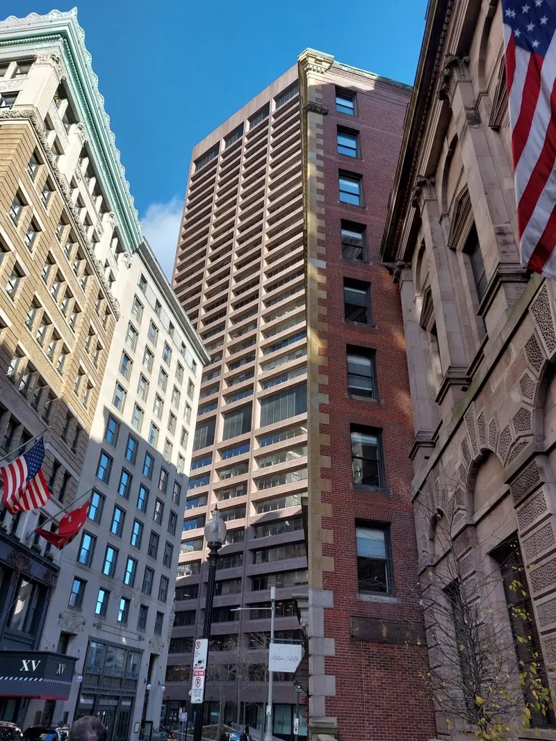 Looking up between high-rise buildings and flags on a Boston street