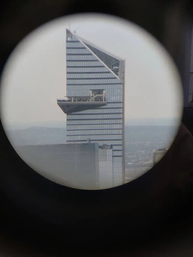 The Edge, with its jutting observation deck, seen through a binocular viewer