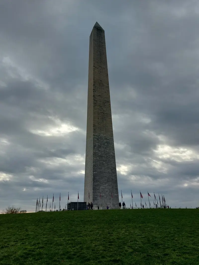 The Washington Monument under a cloudy sky, ringed by flags