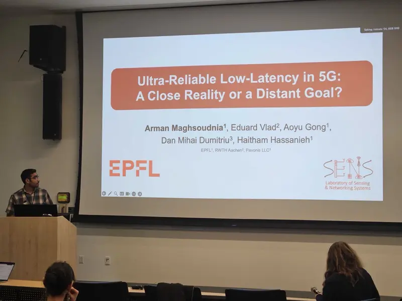 The speaker at the lectern beside the title slide of our HotNets 2024 talk